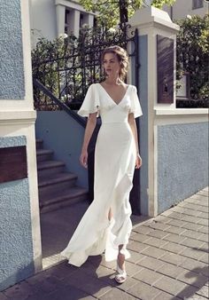 a woman in a white dress is walking down the street with her hand on her hip