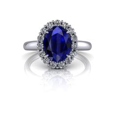 an oval blue sapphire and diamond halo engagement ring in yellow gold with diamonds around the band