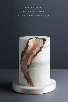 a marbled effect cake with white frosting and gold leaf decoration on the top