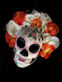 a skull with flowers on it's head sitting in front of a black background