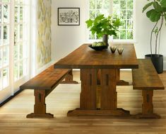 a wooden table with two benches next to a potted plant on top of it