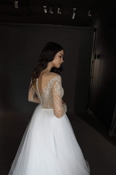 a woman in a white wedding dress is looking back at the camera and she has her hands on her hips