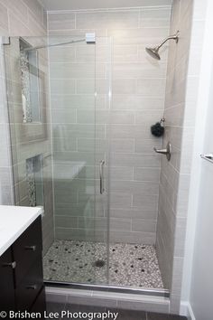 a walk in shower sitting next to a white sink and counter top under a faucet