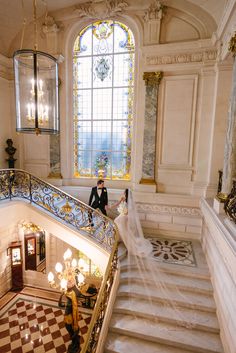 the bride and groom are walking down the stairs at their wedding ceremony in an ornate building