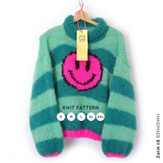 a green and pink sweater with a smiley face on it