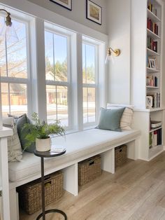 a white window seat with two windows and some bookshelves in the back ground