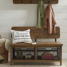 a wooden bench sitting next to a wall with hooks on it and a pillow that says reserved for the dog