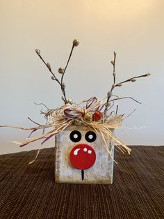 a vase with some branches in it and a face painted on the front, sitting on a table