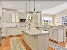 a large kitchen with white cabinets and an island in the middle of the living room