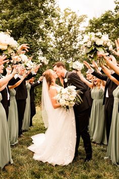 a bride and groom kissing in front of their wedding party