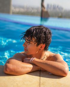 a young man sitting in the middle of a swimming pool