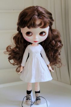 a doll with long brown hair wearing a white dress