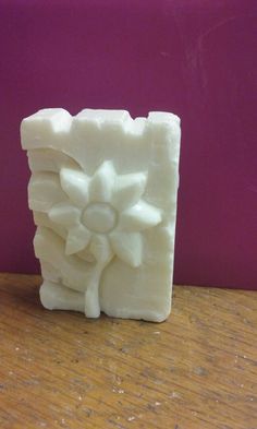 a white soap block sitting on top of a wooden table next to a purple wall