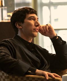 a man sitting in a chair with his hand on his chin and looking off to the side