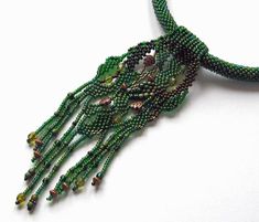 a green beaded necklace on a white surface with beads hanging from it's sides