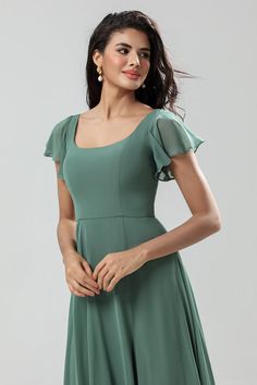 a woman in a green dress posing for the camera with her hands on her hips