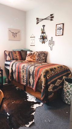 a room with a bed, chair and other items on the wall above it that is decorated in southwestern style