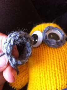 a hand holding a knitted toy with eyes