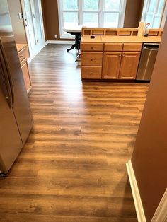 an empty kitchen with wood floors and stainless steel appliances in the middle of the room