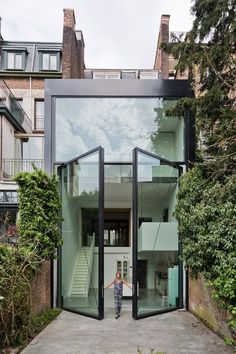 a person standing in front of a glass building with stairs leading up to the second floor