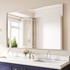 a bathroom vanity with two sinks and a large mirror above it, in front of a window