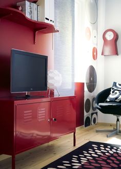 a living room with a red cabinet and black chair in front of the television set