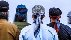 several men wearing turbans and standing in a line with their backs to the camera