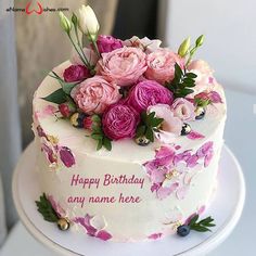 a white cake with pink and purple flowers on it's icing is sitting on a table