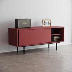 a red cabinet sitting on top of a hard wood floor next to a white wall