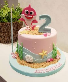 a pink and blue birthday cake with a shark on top