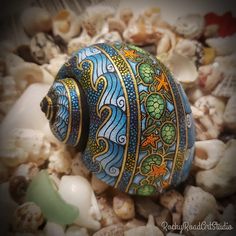 an artistically painted vase sitting on top of sea shells