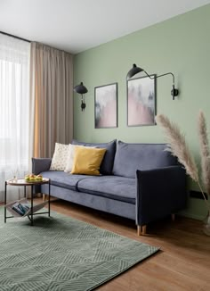 a living room with green walls and wood flooring, two paintings on the wall