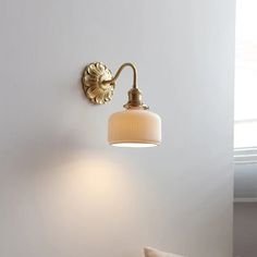 a white bed sitting under a light next to a wall mounted lamp in a bedroom