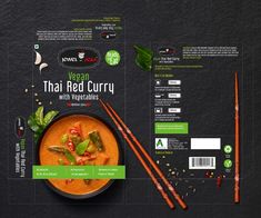 a bowl of red curry next to chopsticks on a black surface with green leaves