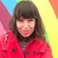 a woman standing in front of a rainbow colored wall