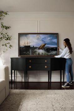 a woman standing in front of a painting on a table