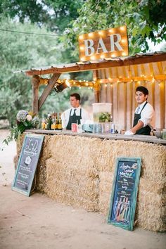 two men standing behind a bar with hay on it