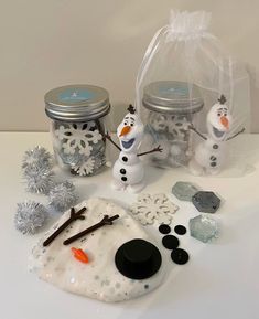 some snowmen are sitting on a table with glass jars and other items to make them look like they're ready for christmas