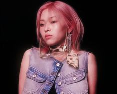 a woman with pink hair wearing a denim vest