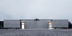 the concrete house is surrounded by grass and trees