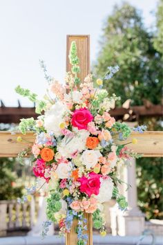 a cross decorated with colorful flowers and greenery