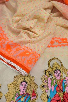 an orange and white saree is laying on top of a table with other items