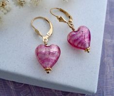 "✦These small pink puffy heart Venetian Murano glass earrings have hues of rubino pink stripes that are enhanced with white gold foil in the interior of the Venetian Murano hearts.  ✦Venetian Murano hearts measure 12mm (a little less than 1/2\") in length and width and are ~7mm (~1/3\") thick. Adorned with graduated sterling silver daisy spacers.  ✦Ear wires: select from sterling silver or 14k gold filled French hook or lever back style. The length of the earrings is 1.3 inches. ✦Want to upgrade your earrings with solid 14k gold ear wires? Click here to purchase the upgrade: https://www.etsy.com/listing/1198680050 ✦Need to convert your earrings to clip-on, non-pierced ear wires? Click here to purchase the upgrade: https://www.etsy.com/listing/706005409 ✦Matching necklace available: https:/ Nickel-free Pink Heart Cut Jewelry, Pink Round Heart Earrings For Valentine's Day, Pink Lever Back Earrings For Anniversary, Pink Earrings With Lever Back For Anniversary, Pink Gold Heart Earrings For Gift, Pink Hypoallergenic Jewelry For Valentine's Day, Pink Gold Jewelry With Ear Wire For Gifts, Hypoallergenic Pink Gold Earrings Gift, Tiny Gold Earrings