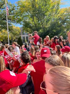 a large group of people in red shirts and hats are gathered around each other on the street