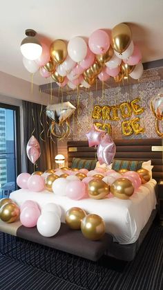 a bedroom decorated with balloons and streamers in gold, pink, and white colors