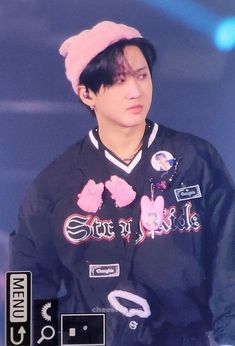 the young man is wearing a black jacket and pink beanie on top of his head