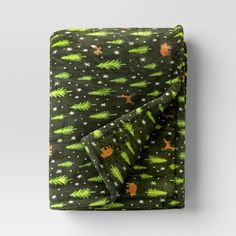 a green blanket with stars and trees on it is folded up in front of a white wall