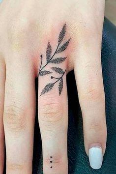 a woman's hand with a small tattoo on the middle finger and an olive branch