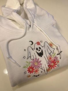 Floral Ghost Embroidered Sweatshirt! It couldn't be fall season without the perfect fall sweater! Embroidered on Gildan 50/50 Cotton/Polyester Blend. Using fall colors, our machine embroiders the cutest fall crewnecks! The perfect outfit for fall outings, watching movies, or going to the pumpkin patch! Embroidered Hoodie For Fall Streetwear, Hooded Hoodie With Machine Embroidery For Streetwear, Cute Embroidered Hoodie For Streetwear, Long Sleeve Sweatshirt With Machine Embroidery For Streetwear, Long Sleeve Embroidered Sweatshirt For Streetwear, Halloween Cotton Hoodie Sweatshirt, Cute Hooded Hoodie With Embroidered Logo, Fall Embroidered Logo Long Sleeve Hoodie, Fall Hoodie With Embroidered Logo And Long Sleeves