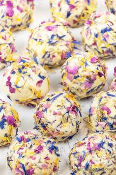 colorful sprinkles and white chocolate balls are on a sheet of parchment paper